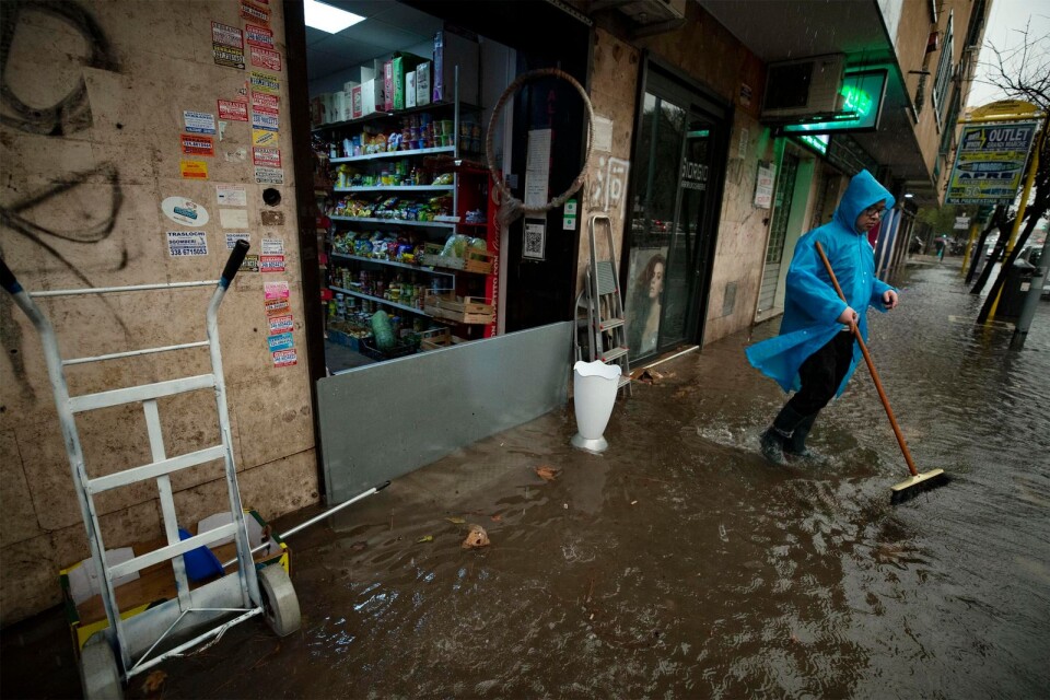 En man försöker få bort vatten från trottoaren utanför sin butik i Rom, efter de kraftiga skyfallen som lett till översvämningar på flera håll i Italien. Bilden är från i torsdags.