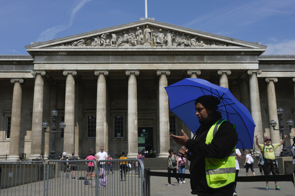 A worker holding an umbrella guides the tourists at British Museum during a hot weather day in Central London, Monday, June 12, 2023. (AP Photo/Kin Cheung) XKC103