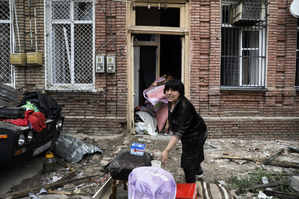 En familj försöker rädda tillhörigheter ur ett hus i Gjandzja, Azerbajdzjan, som tros ha beskjutits från armeniskt håll.