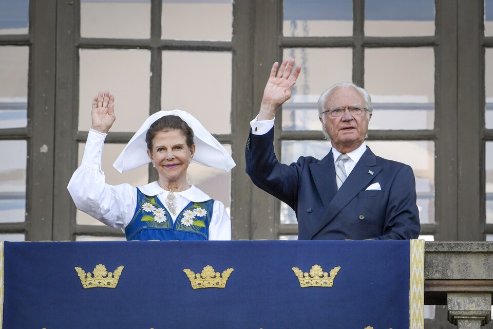 Drottning Silvia och kung Carl XVI Gustaf på Logården framför Stockholms slott i samband med nationaldagsfirandet.