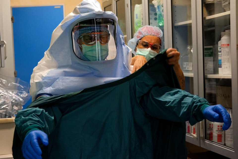 En sjuksköterska hjälper en kollega att sätta på sig skyddsutrustning vid en covid-19-avdelning i Rom i mitten av april.