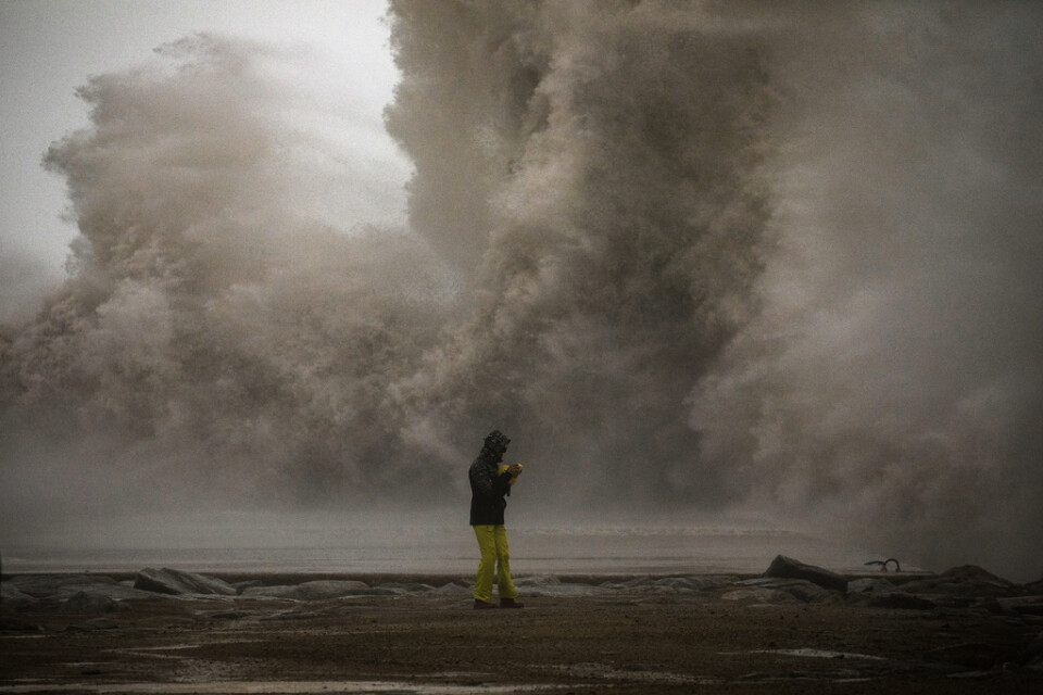 En kvinna i Barcelona fotograferar ett stormigt Medelhav. Bild tagen den 21 januari.