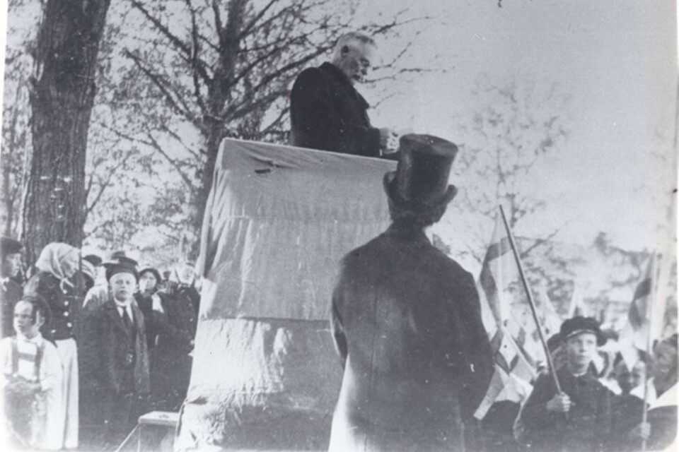 Ordningsmannen Ernst Julius Jeanzén håller tal på torget vid 100-årsjubiléet 1920. Längst ner till höger syns skolpojken Gunnar Nyqvist och längst till väsnter i huckle, Ida Sparring.