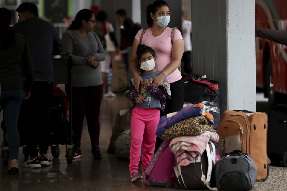 Resenärer med munskydd vid busscentralen i Colombias huvudstad Bogotá på fredagen.