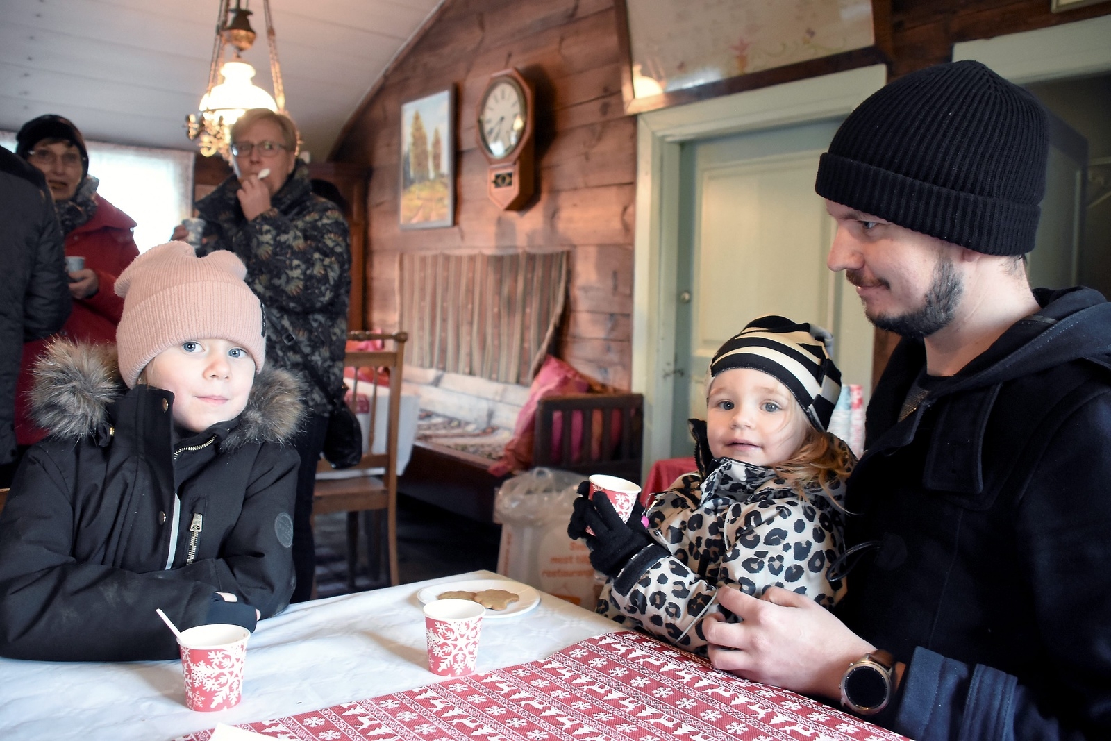 Tyra och Ellie Hansen har en mysig stund med glögg och pepparkakor tillsammans med pappa Emil Hansen. Foto: Helén Fingalsson