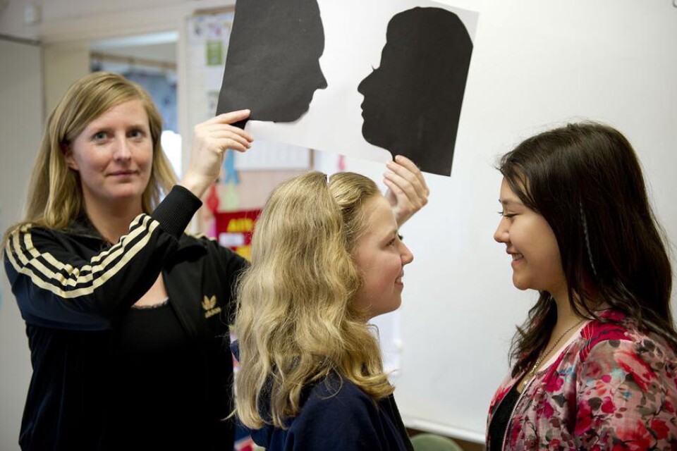 Tilda Lönngren och Tove Beckman ritade siluetter. Läraren Madeleine Johansson visar upp tjejernas konstverk.