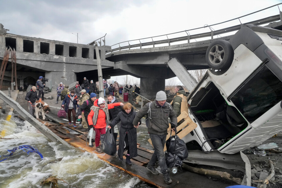 Människor på flykt från samhället Irpin i utkanten av Kiev via en provisorisk övergång vid den förstörda bron på måndagen.