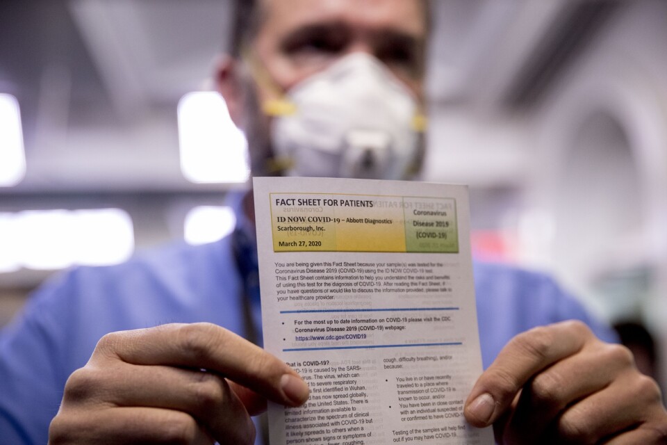 En journalist håller upp ett informationsblad efter att ha genomgått ett snabbtest för coronavirus i Vita huset.