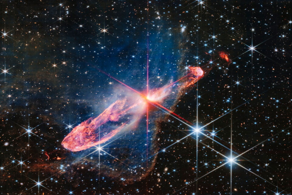 Stjärnorna Herbig-Haro 46/47, som befinner sig 1|470 ljusår bort, är i mitten av de röda "linjerna". Det så kallade frågetecknet är i nedre kanten av bilden, lite till höger om mitten.