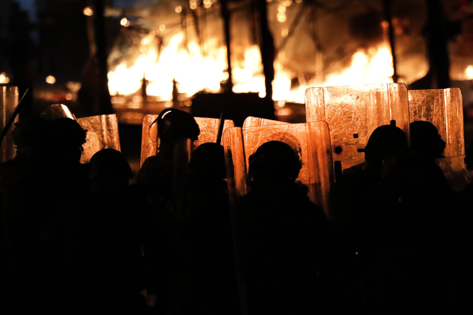 Kravallpolis framför tält som satts i brand i Beirut i Libanon. Tälten tillhörde regeringskritiska demonstranter.