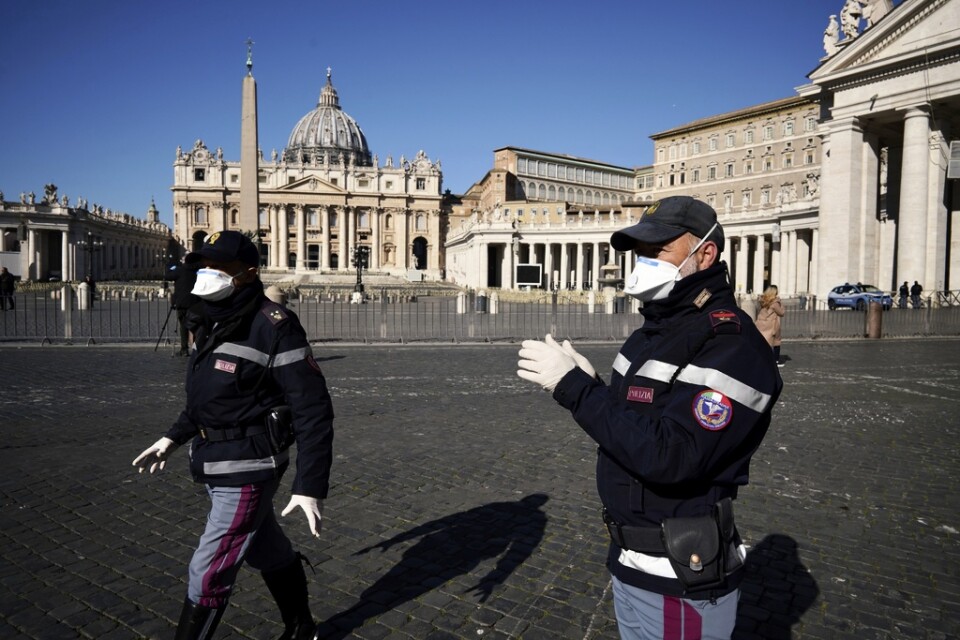 Polis i munskydd patrullerar i ett tomt Vatikanen i veckan.