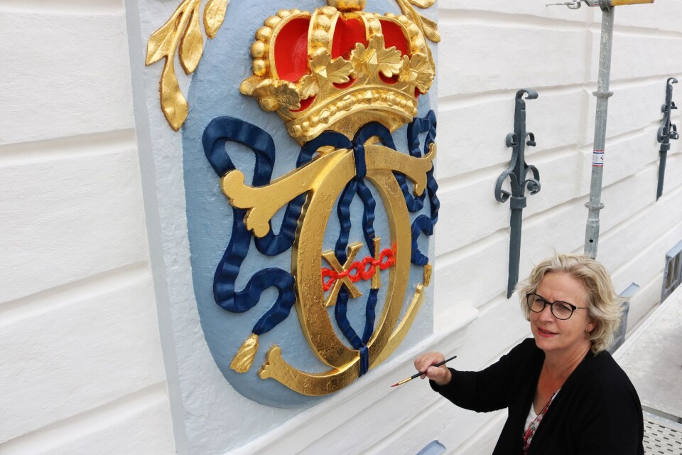 Den skyddande plasten blåste bort under natten, så dekorationsmålaren Anne Håkansson gjorde några sista justeringar av den cinnoberröda färgen i kung Karl XI:s namnchiffer som pryder rådhusets fasad.