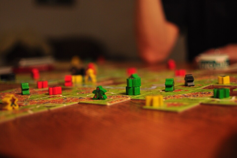 Spelpjäserna, eller ”Meeples” är utplacerade på spelplanen för att erövra städer och vägar i strategispelet Carcassonne.