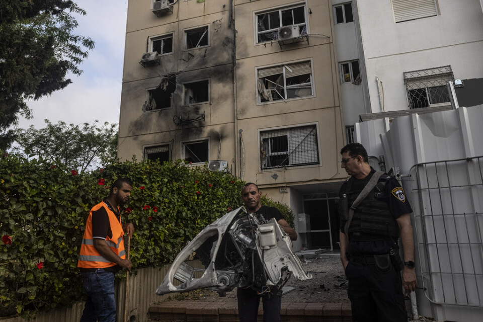 Förstörda hushållsapparater bärs ut från det träffade huset i iraeliska Ashkelon.