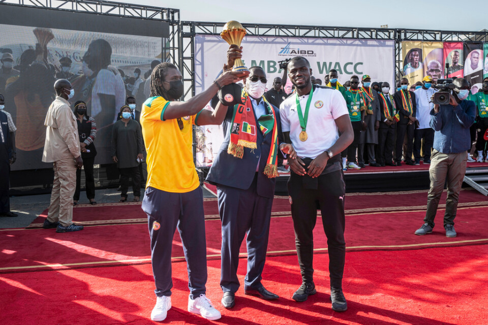 Förbundskapten Aliou Cissé, president Macky Sall och lagkaptenen Kalidou Koulibaly poserar med pokalen.