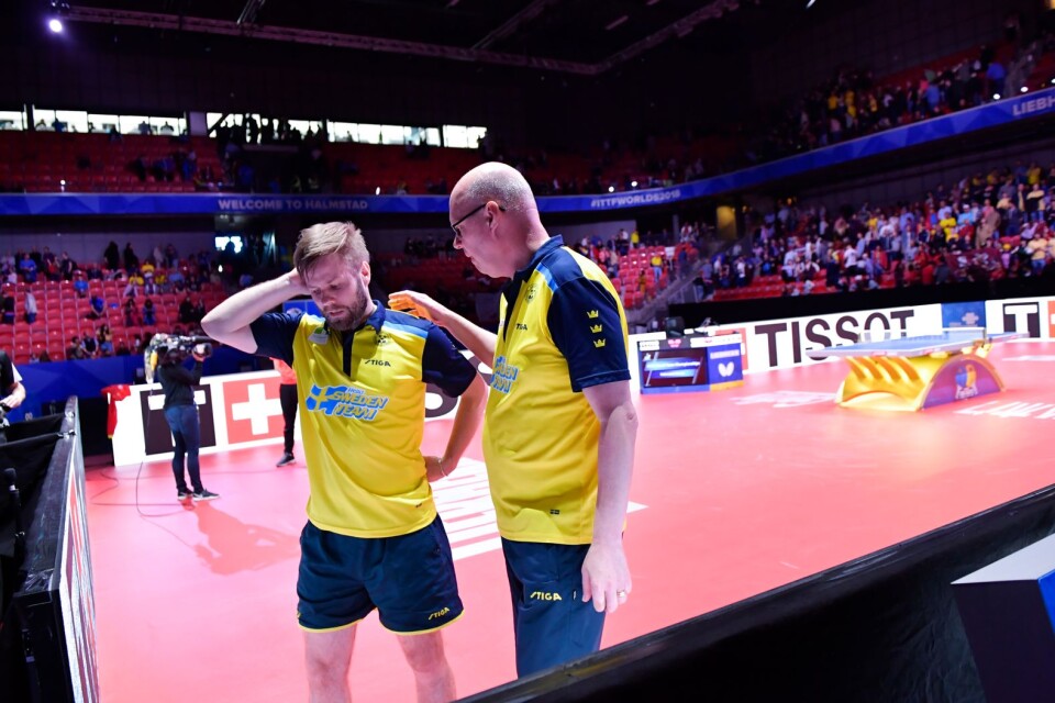 Sveriges Jon Persson tröstas av förbundskapten Ulf "Tickan" Carlsson efter förlustmatchen mot Kinas Xu Xin i semifinalen under lag-VM i bordtennis i Halmstad  Arena. En förlust som innebar att Sverige föll med 3–0 i matcher.
