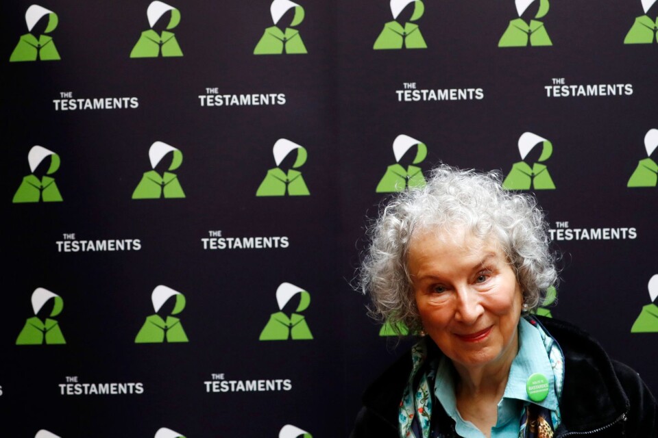 Margaret Atwood bär grönt på presskonferensen i London och omges av två kvinnor i fotsida klänningar – dock inte i rött som i tv-serien "Handmaid's tale". "Vi har nya kostymer, för det skulle regimen ha haft", konstaterar Atwood.