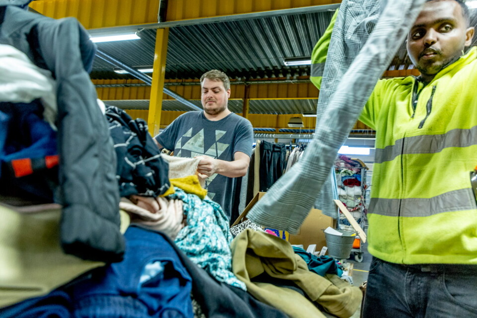 Magnus Schüler och Isak Nur går igenom en av klädhögarna på Myrornas sorteringscentral i Göteborg.