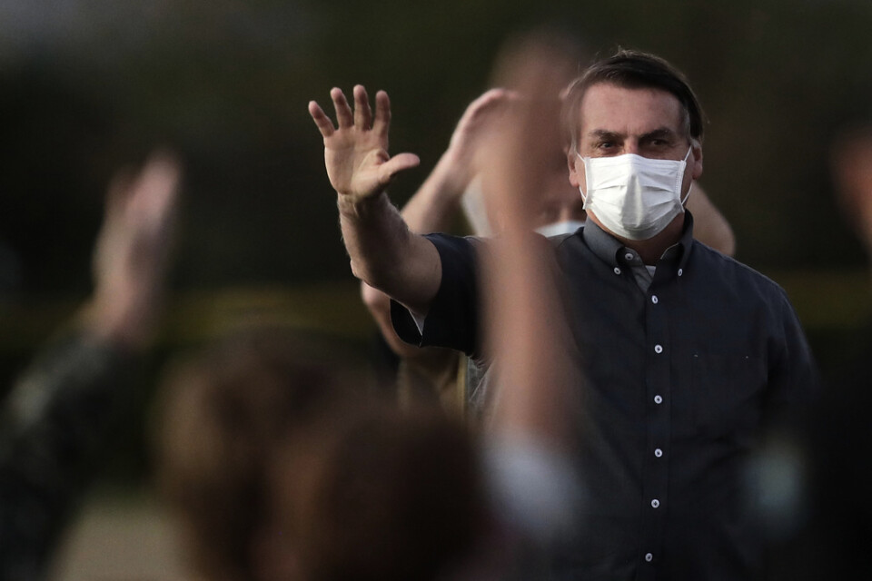 Den covid-19-smittade Jair Bolsonaro vinkar till anhängare under ett evenemang i Brasília på måndagen.