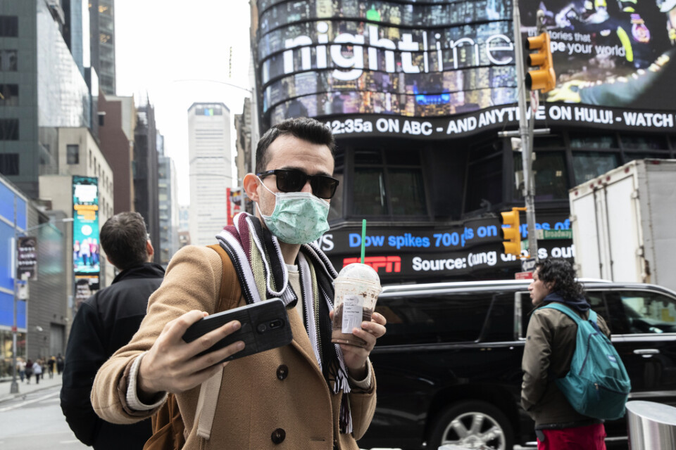Den albanske turisten Justin Dalipi bär munskydd för att skydda sig mot coronaviruset under sitt besök i New York – men tar ändå en så kallad selfie.