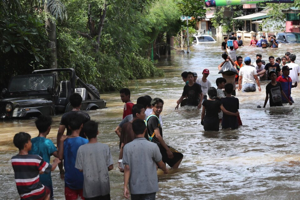 Folk vadar genom ett översvämmat område i Tanggerang utanför Indonesiens huvudstad Jakarta.