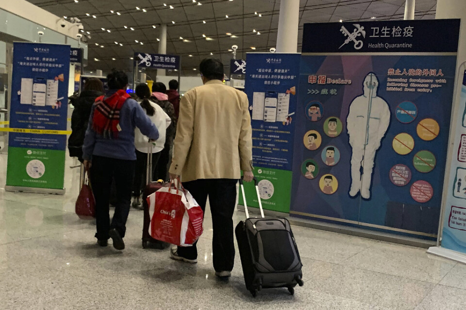 Resenärer passerar en hälsokontroll på den internationella flygplatsen i Peking den 13 januari.