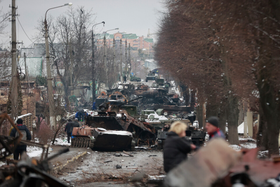 Människor tittar på förödelsen av ryska militära fordon på en väg i Butja utanför Kiev, i en bild från i tisdags.