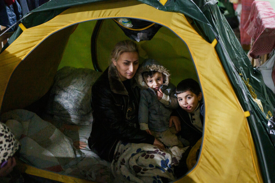 En kvinna med två barn sitter i ett tält i lägret belarusiska Bruzgi, någon kilometer från Polen. Bild tagen 23 december 2021.