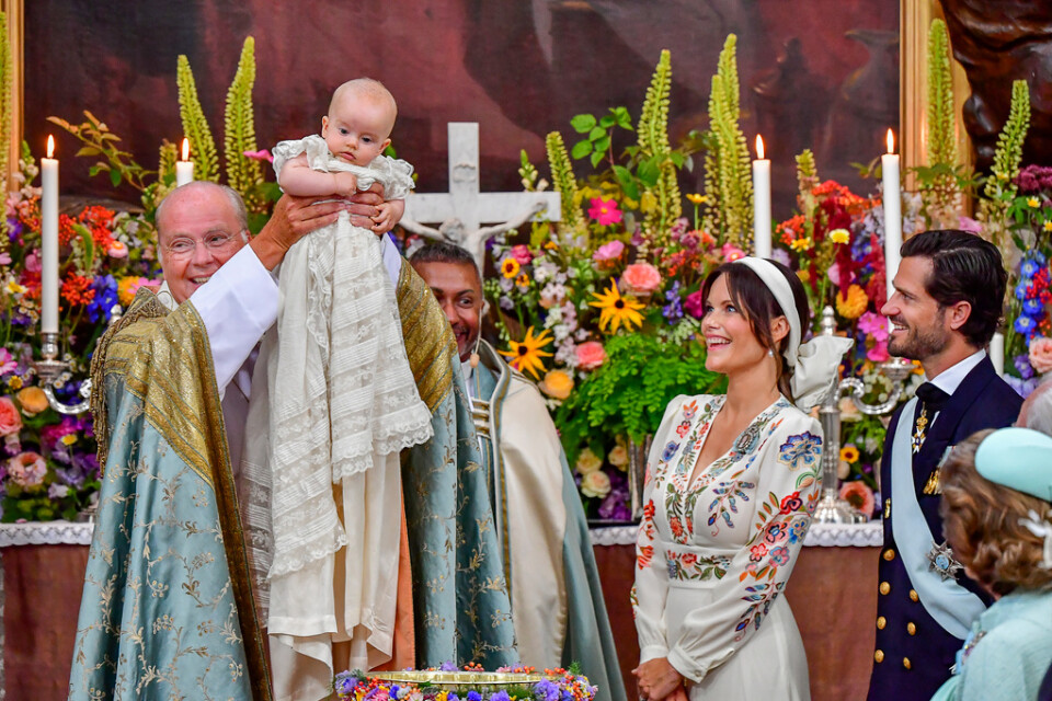 Biskop Johan Dalman håller upp den nydöpte prins Julian som beundras av hovpredikant Michael Bjerkhagen, prinsessan Sofia och prins Carl Philip.