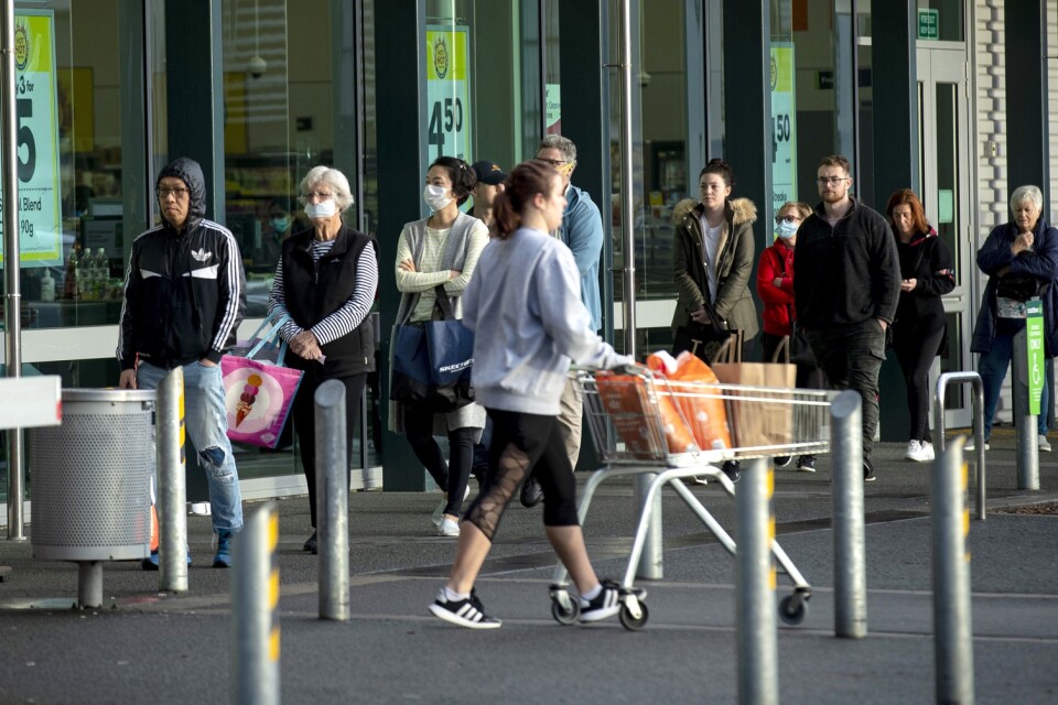 Människor köar utanför en livsmedelsbutik i Auckland.