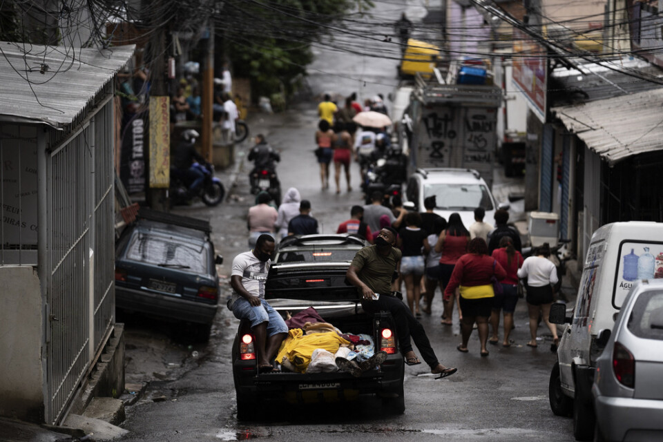 Invånare i favelan Complexo do Alemão i norra Rio de Janeiro, Brasilien, går med en bil som fraktar flera dödsoffer efter en polisstats.