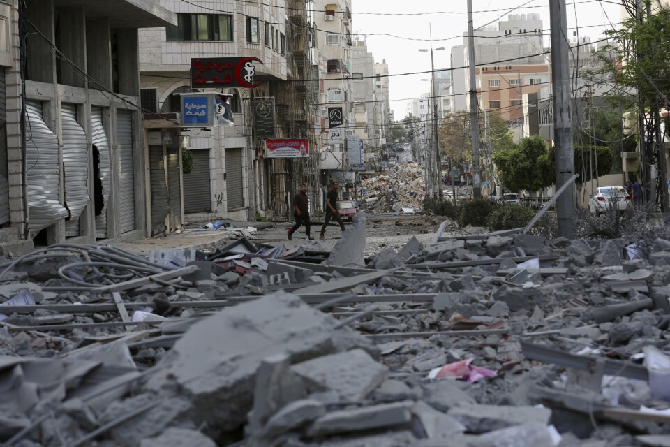 Människor inspekterar resterna av en bombad kommersiell by7ggnad och en vårdklinik i staden Gaza.