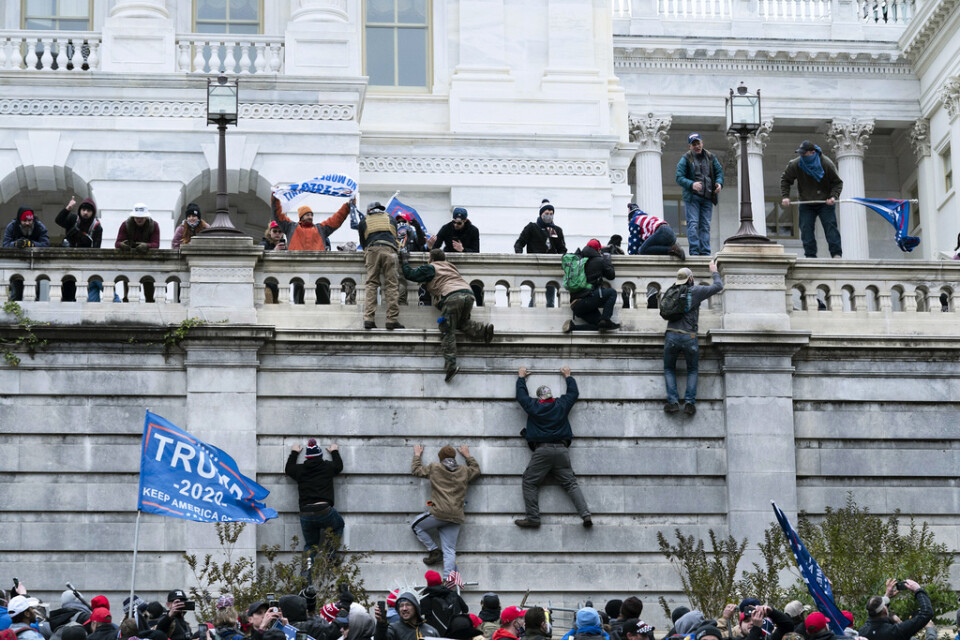 Anhängare till president Donald Trump försöker klättra upp för en mur vid kongressbyggnaden Kapitolium.