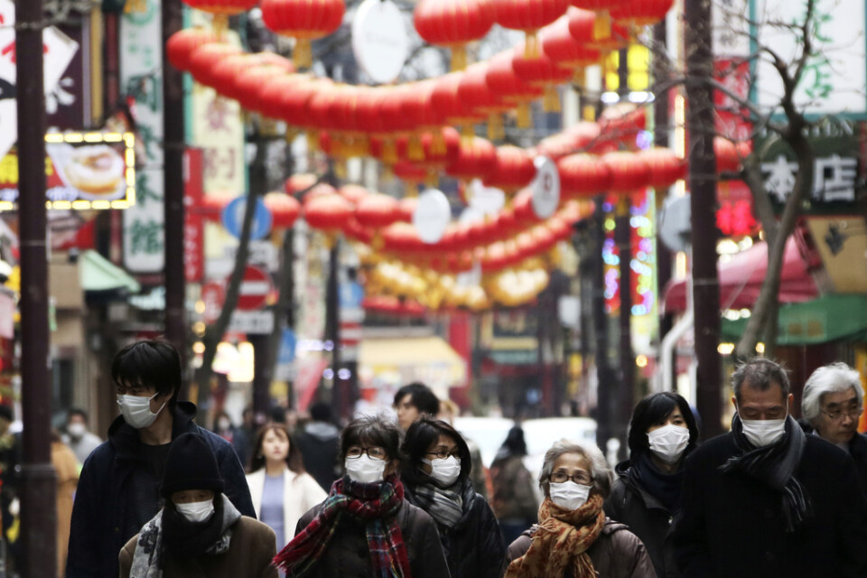 Människor i ansiktsmundering i Chinatown-området i Yokohama, Japan.