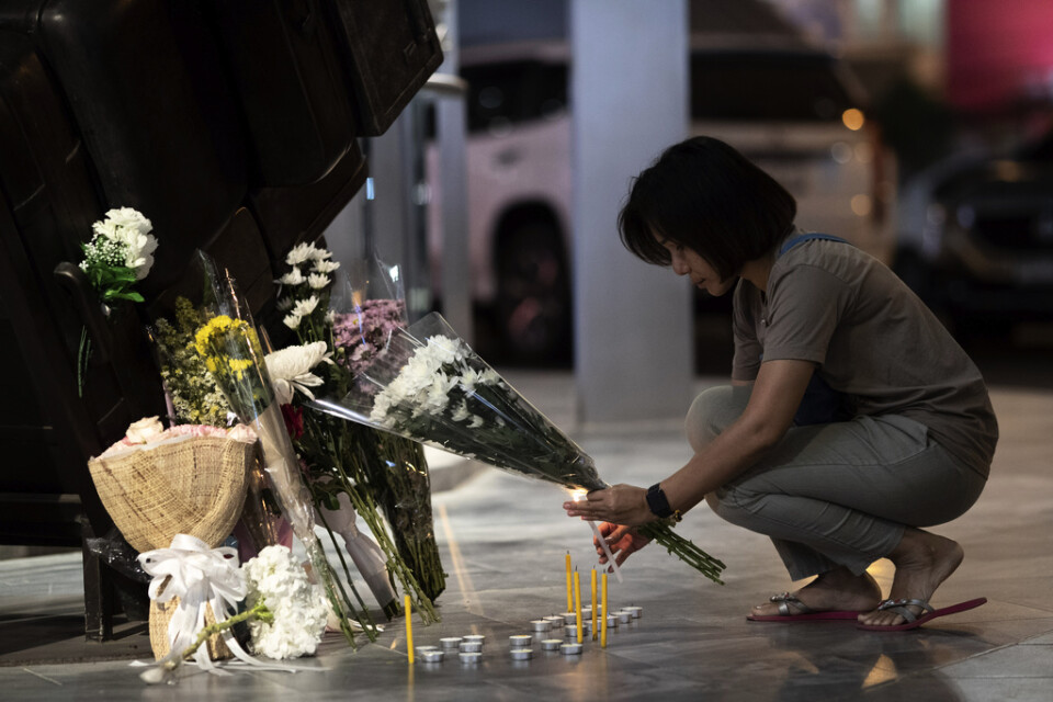 En kvinna lägger ned blommor utanför köpcentret Terminal 21 där massmördaren barrikaderade sig i samband med skottdådet.