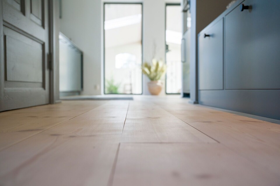 Genom att låta plankorna löpa genom både hallen och köket suddas gränsen mellan inne och ute bort.
