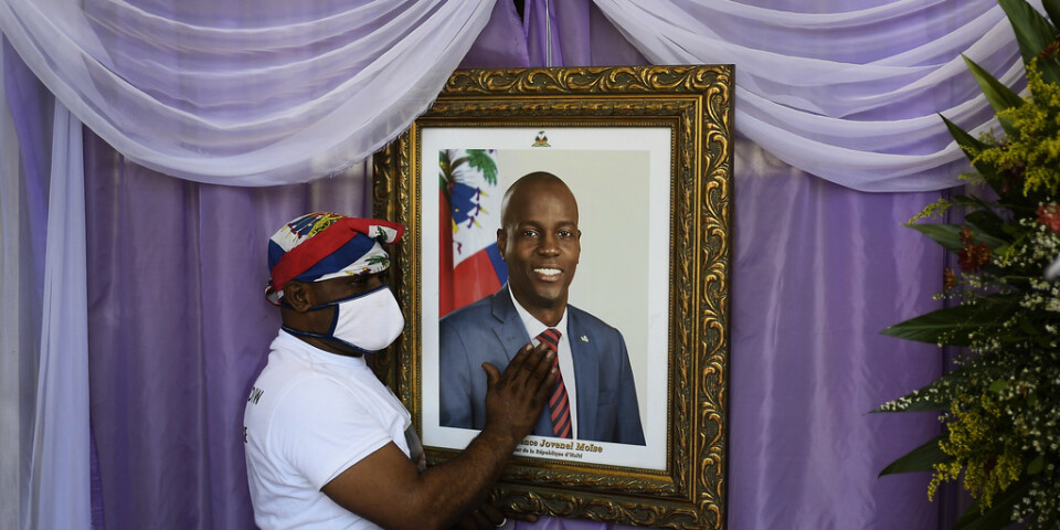 En man rör vid porträttet av den mördade haitiske presidenten Jovenel Moïse utanför en katedral i samband med begravningen. Arkivbild