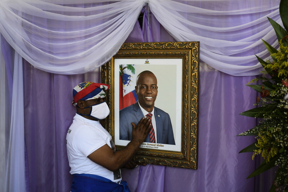 En man rör vid porträttet av den mördade haitiske presidenten Jovenel Moïse utanför en katedral i samband med begravningen. Arkivbild