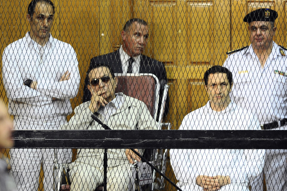 Mubarak bakom galler vid en domstolsförhandling i Kairo 2013 – två år efter den arabiska våren då han tvingades avgå. Till vänster står hans son Gamal Mubarak och till höger sitter sonen Alaa Mubarak. Arkivbild.