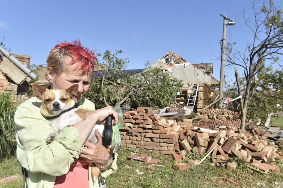 En kvinna med en hund i famnen gråter framför familjens förstörda hus i byn Moravská Nová Ves.