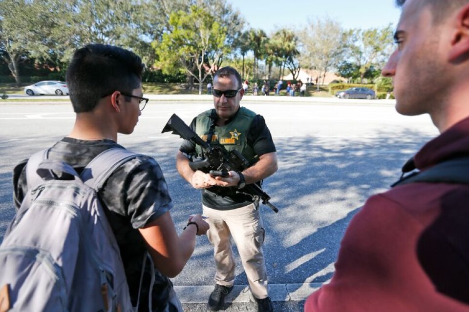 En polisman talar med elever vid skolan i Parkland i Florida efter skottlossningen.