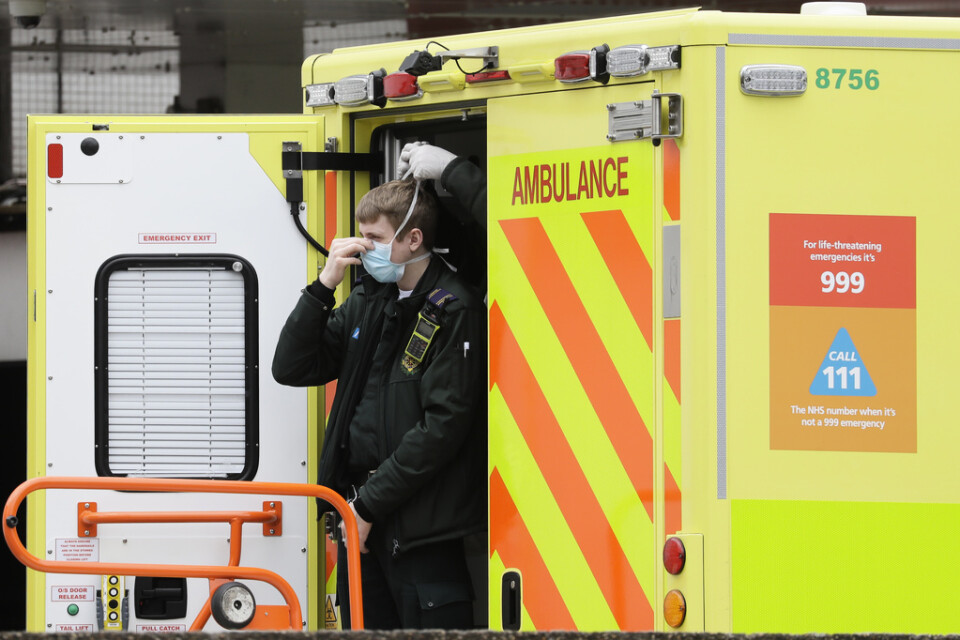 En vårdanställd får hjälp av en kollega att få på sig ett munskydd, vid ett sjukhus i London.