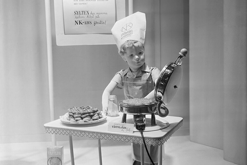 NK:s skyltfönster, 1950. En liten pojke som skyltdocka och som lagar våfflor. Han har kockmössa med NK Livs logotyp.