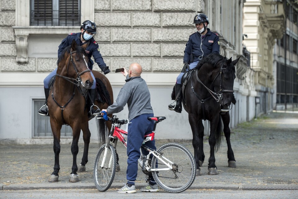 Poliser i Rom kontrollerar att en cyklist har rätt att vara ute och inte bryter mot restriktionerna för att minska smittspridningen.