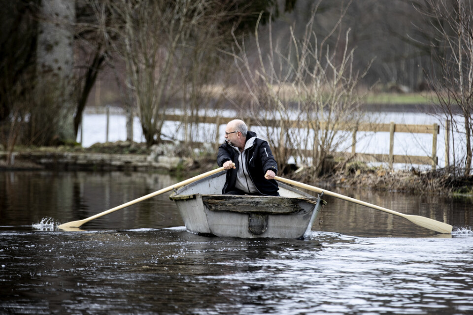 Mikael Jönsson får ta båten mellan hemmet och bilen då vägen är översvämmad vid Nissan i Åled.