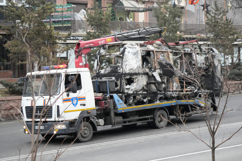 En buss som bränts i våldsamheterna i Almaty transporteras bort på måndagen.