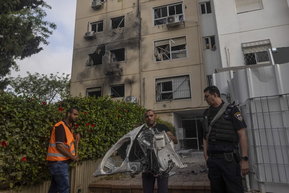 Förstörda hushållsapparater bärs ut från det träffade huset i israeliska Ashkelon.
