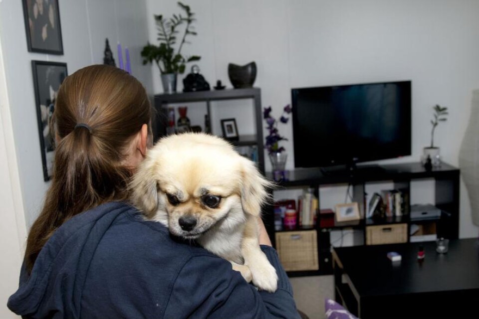 Kim och hennes hund i hennes lägenhet på Kungsljuset. Hon har mött fördomar förr och vill av hänsyn till sin familj inte ha sitt efternamn i tidningen. Foto: Helge Rubin