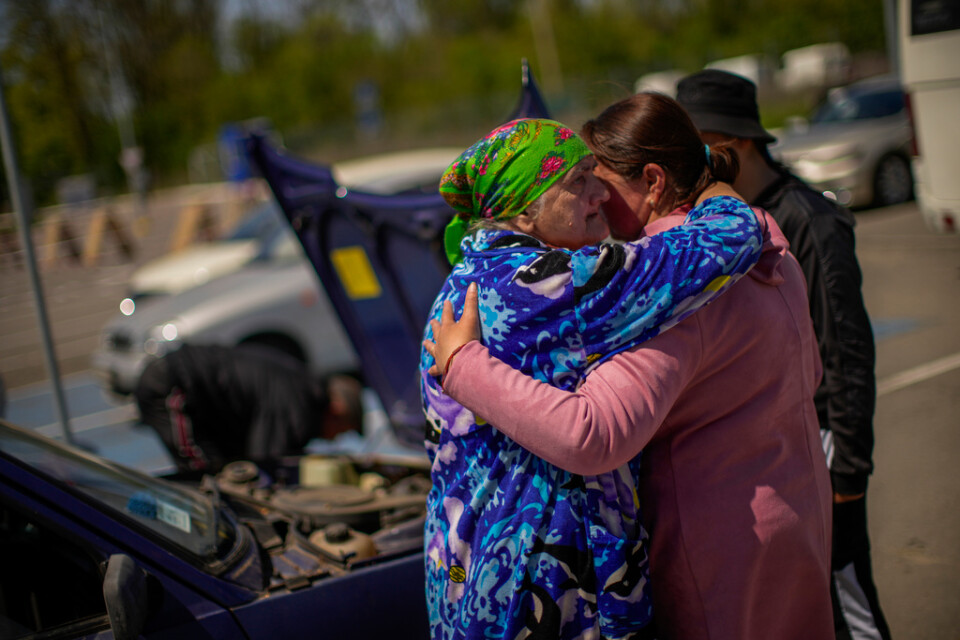 Familjemedlemmar som har flytt från orten Myrne i en bärgad bil omfamnar varandra vid ankomst till Zaporizjzja, där fordonet repareras under söndagen.