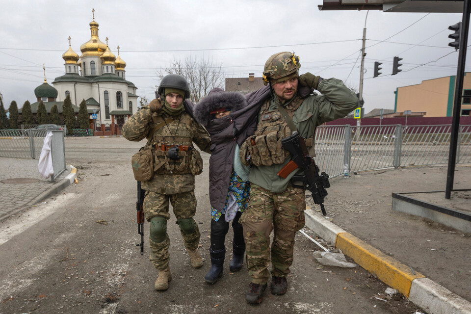 Ukrainska soldater hjälper en kvinna i staden Irpin söndag den 6 mars.